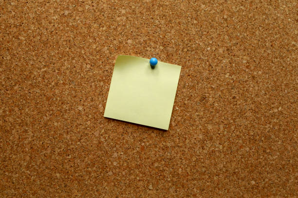 istock Blank yellow notepaper with blue push pin on a corkboard 1271696012