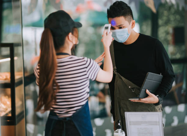 istock asian chinese cafe waitress checking body temperature for client as standard procedure and check in process before entering cafe as new normal 1271696032