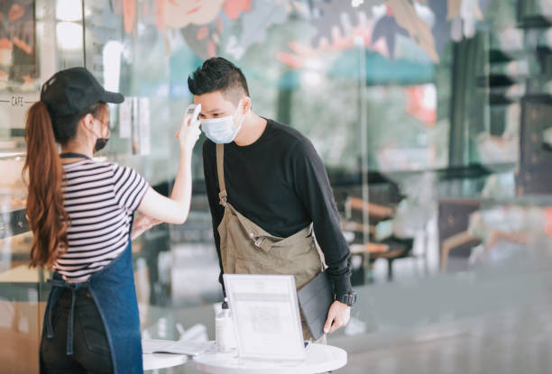 istock asian chinese cafe waitress checking body temperature for client as standard procedure and check in process before entering cafe as new normal 1271696043