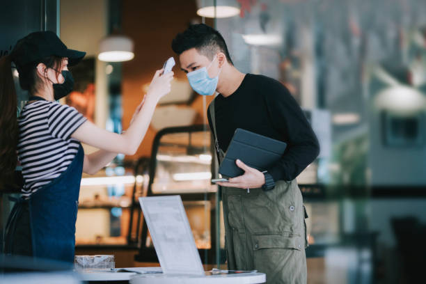istock asian chinese cafe waitress checking body temperature for client as standard procedure and check in process before entering cafe as new normal 1271696069