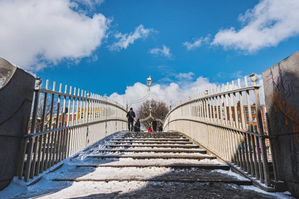 Irish landmark and community: Ha' penny Bridge covered with snow, pedestrian overpass covered by snow. Dublin, Ireland Dublin, Ireland - February 28, 2018

Ha' penny Bridge covered with snow. This pedestrian overpass is a popular historical landmark across River Liffey and connects Temple Bar with the North Inner City bridge crossing cloud built structure stock pictures, royalty-free photos & images