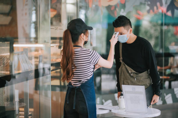 istock asian chinese cafe waitress checking body temperature for client as standard procedure and check in process before entering cafe as new normal 1271696086