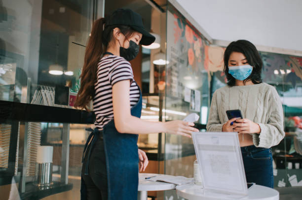 istock asian chinese cafe waitress checking body temperature for client as standard procedure and check in process before entering cafe as new normal 1271696148
