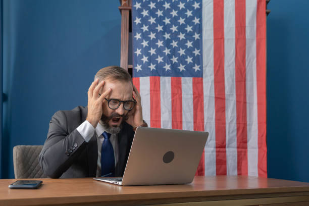 istock Business white vintage american man, caucasian person working from home, thinking about problem with computer notebook laptop and suffering from depression with american or usa national flag. 1271696259
