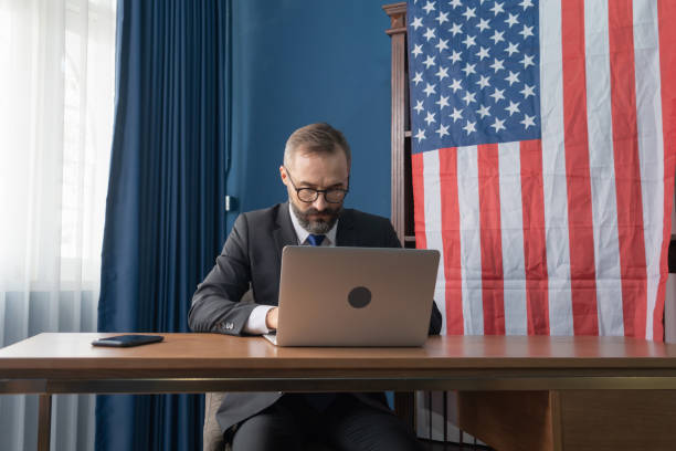 smiling business vintage, white gentleman, caucasian person with american or usa national flag working from home on table with computer notebook laptop on webcam video call conference in quarantine. - state government imagens e fotografias de stock