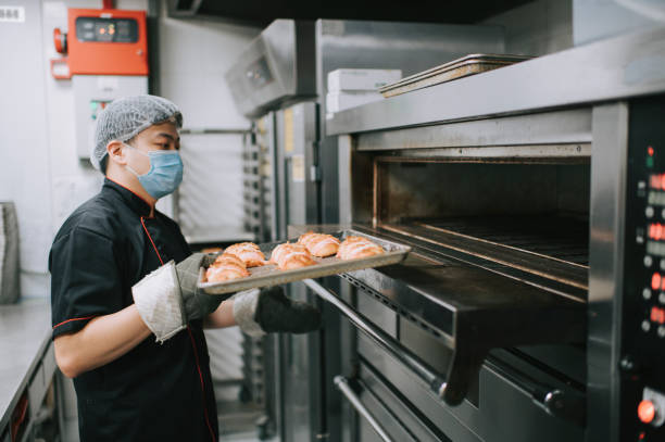 istock commercial kitchen bakery owner baking bread taking out from oven 1271696343