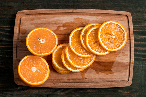 Above view of fresh orange slices on wooden board placed on kitchen table, ingredient for mulled wine
