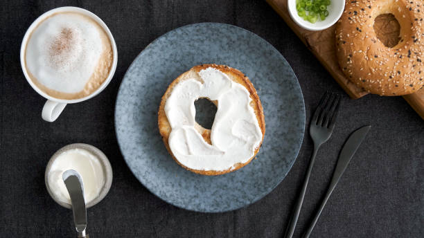 Toasted bagel with cream cheese Toasted bagel with cream cheese and cup of coffee for breakfast, top view cream cheese photos stock pictures, royalty-free photos & images