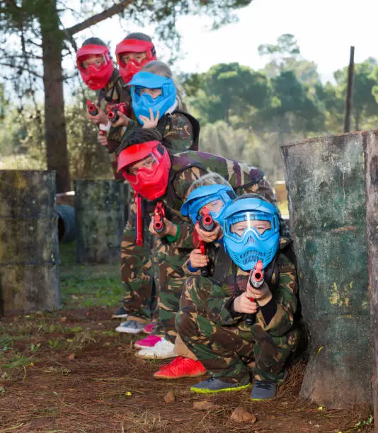 Photo of Kids paintball players aiming outdoors