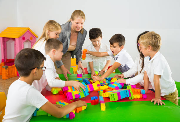 istock Kids and teacher playing with toy building blocks 1271705062