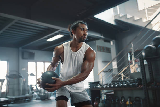 Man On Kettlebell Workout. Sexy Asian Sportsman With Strong, Healthy, Muscular Body Using Heavy Fitness Equipment. Training At Gym For Bodybuilding As Lifestyle. Man On Kettlebell Workout. Sexy Asian Sportsman With Strong, Healthy, Muscular Body Using Heavy Fitness Equipment. Training At Gym For Bodybuilding As Lifestyle. fitness trainer stock pictures, royalty-free photos & images