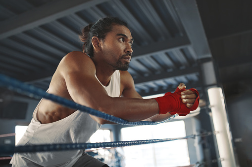 Photo of a young and handsome boxer with muscular build body with red gloves training in a gym