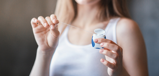 Oral hygiene concept. Closeup view of young girl holding dental floss indoors, panorama