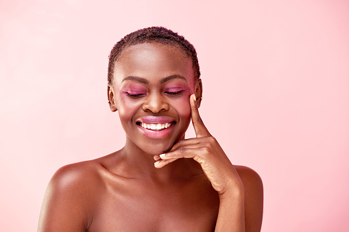 Studio shot of a beautiful young woman posing against a pink background