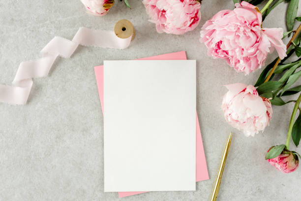 istock Mockup invitation, blank paper greeting card, pink envelope and peonies on gray stone table. Flower background. Flat lay, top view 1271708139
