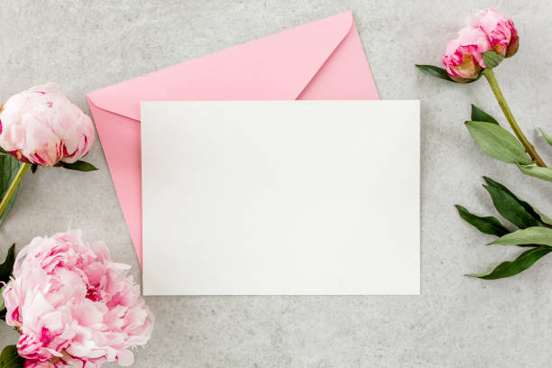 istock Mockup invitation, blank paper greeting card, pink envelope and peonies on gray stone table. Flower background. Flat lay, top view 1271708716