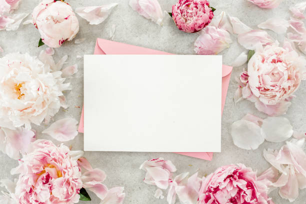 istock Mockup invitation, blank paper greeting card, pink envelope and peonies on gray stone table. Flower background. Flat lay, top view 1271709076