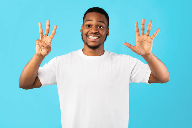 istock Black Man Showing Number Eight Counting On Fingers, Blue Background 1271709231