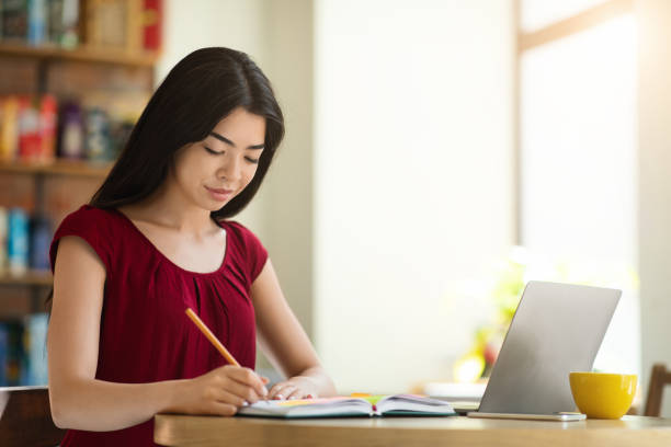 istock Beautiful Asian Student Girl Studying With Laptop In Cafe And Taking Notes 1271709244