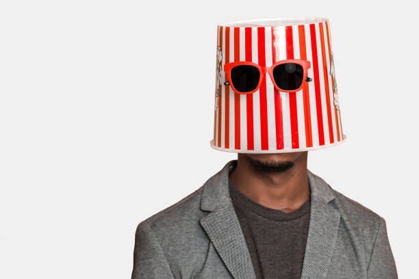 Unrecognizable black guy in bucket and sunglasses Anonymous African American man wearing striped popcorn bucket with sunglasses on head against gray background vogue cover stock pictures, royalty-free photos & images