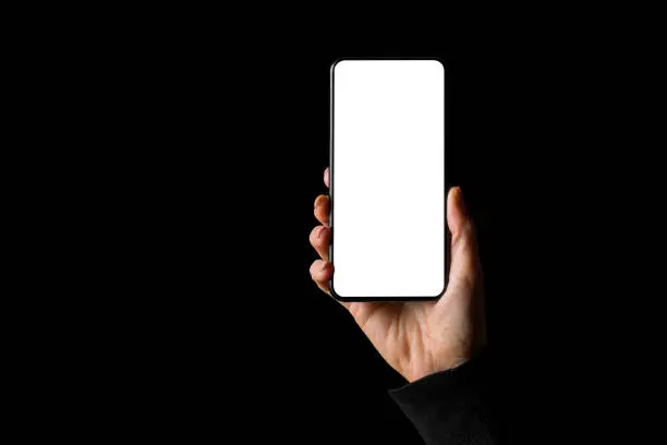 Person holding in hand smartphone with empty white screen, isolated on black background