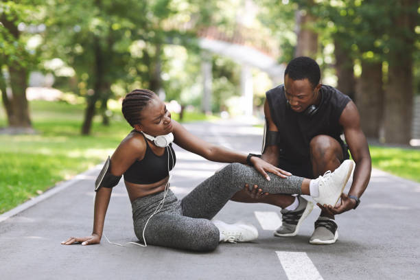Caring Black Man Massaging Injured Leg Of Girlfriend After Running Together Outdoors Caring Black Man Massaging Injured Leg Of Girlfriend After Running Together Outdoors, Free Space sprain stock pictures, royalty-free photos & images