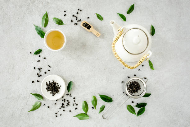 istock Herbal tea with two white tea cups and teapot, with green tea leaves. Flat lay, top view. Tea concept 1271713582