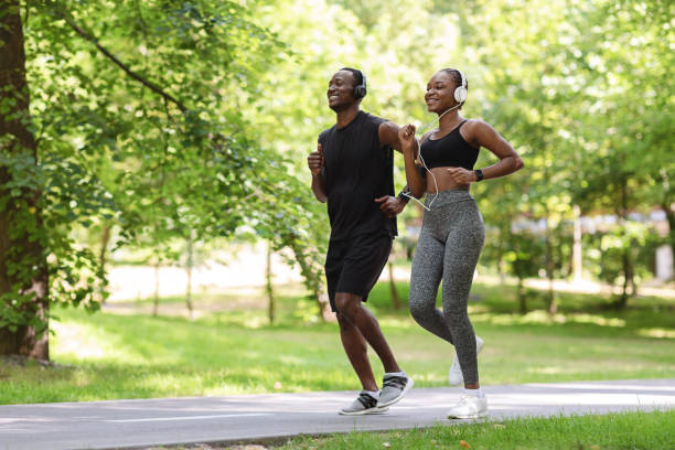 morgon spring. sportig svart kille och tjej jogging tillsammans i green park - park run bildbanksfoton och bilder