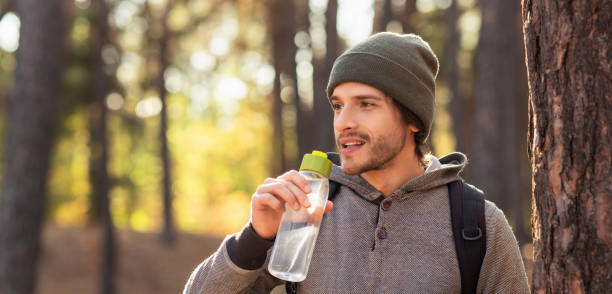 istock Closeup of young man drinking water in forest 1271714226