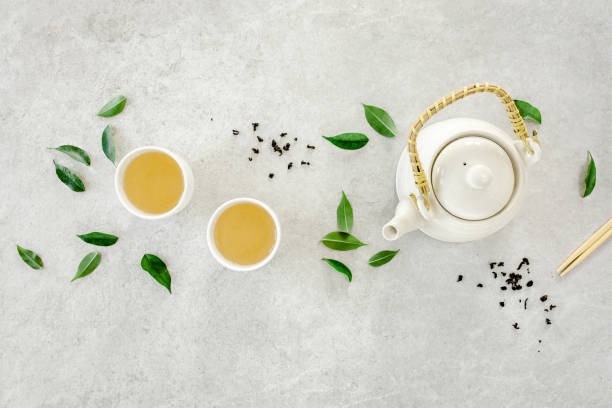 istock Herbal tea with two white tea cups and teapot, with green tea leaves. Flat lay, top view. Tea concept 1271714276