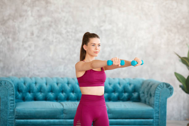 istock Home training. Strong young woman doing exercises with dumbbells at home 1271714931