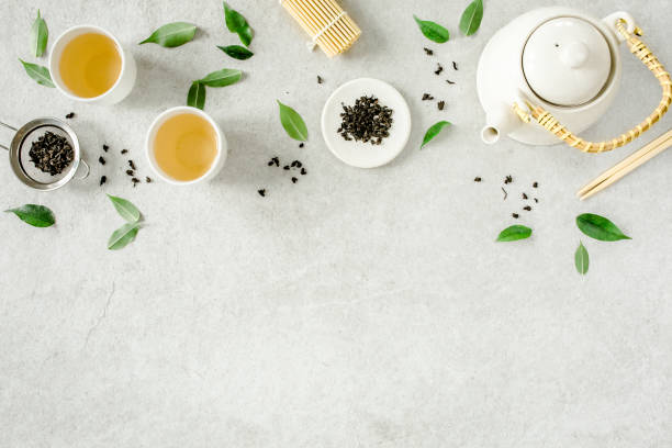 istock Herbal tea with two white tea cups and teapot, with green tea leaves. Flat lay, top view. Tea concept 1271715737