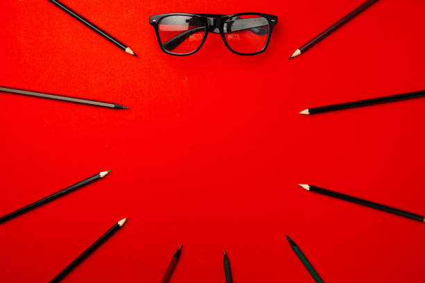 istock Black pencils and glasses on red background top view 1271717811