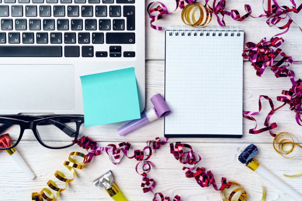Office desk with laptop and open notepad  decorated with party streamers