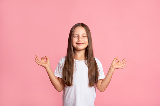Photo portrait of charming little girl raise fists excited scream yes lucky wear trendy white clothes isolated on orange color background.