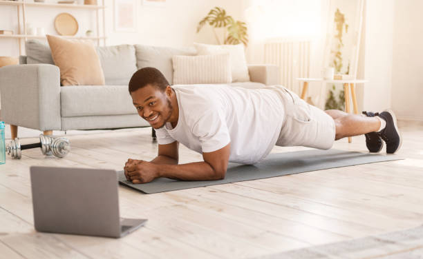 istock African Guy Training At Laptop Doing Plank Exercise In Bedroom 1271722534