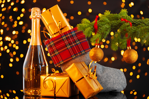 Champagne bottle and Christmas stocking with gifts against garland