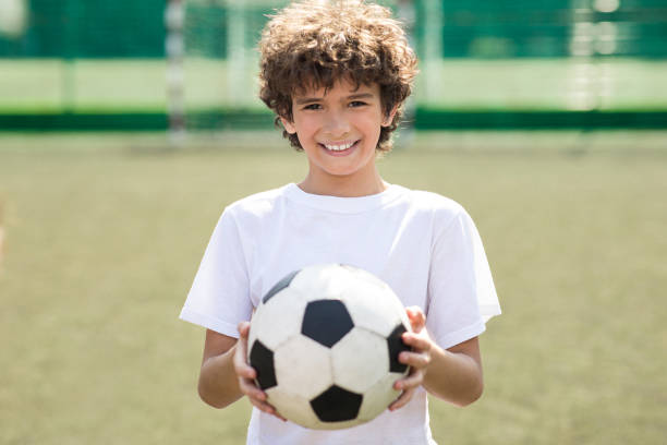 istock Boy holding soccer ball on the field 1271723950