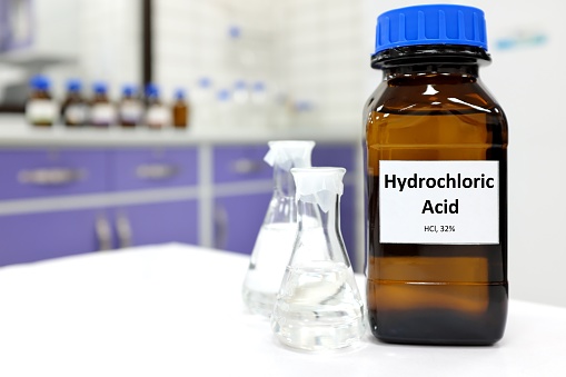 Selective focus of strong hydrochloric acid chemical in brown amber glass bottle inside a laboratory with copy space.