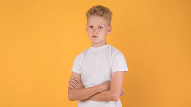 istock Portrait of sad boy with folded arms standing at studio 1271725081