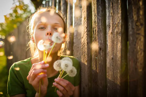 Portrait of happy young woman relaxing on a lovely summer day,  playing with dandelions