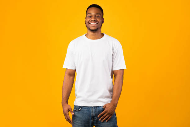 hombre negro sonriendo a la cámara posando, fondo amarillo, disparo de estudio - mens shirt fotografías e imágenes de stock