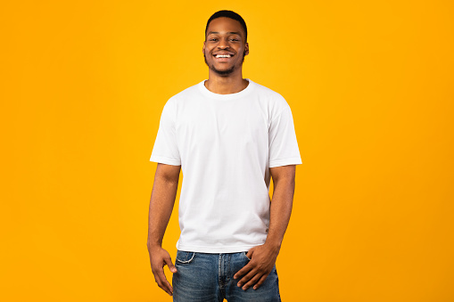 Happy Black Man Smiling To Camera Posing Standing Over Yellow Background, Studio Shot. Good Mood Concept