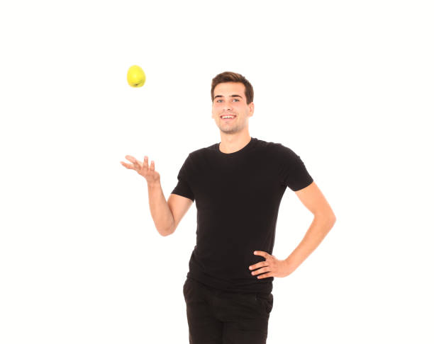 istock Smiling young handsome man is throwing yellow apple isolated on white. Copy space and selective focus 1271726860