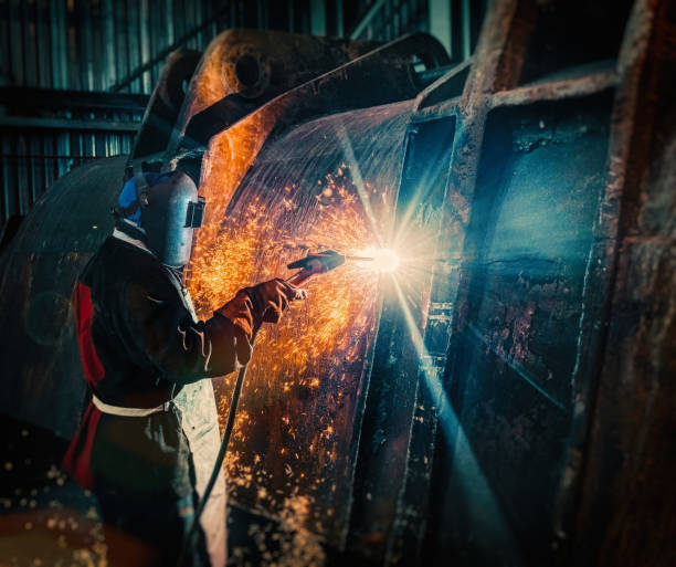 afrikanischer arbeiter schweißt eine gigantische bergbauschaufel - welder manual worker african descent steel worker stock-fotos und bilder