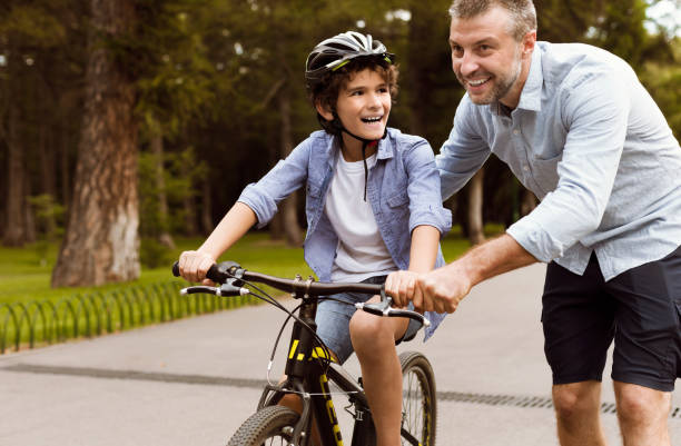 istock Boy learning to ride a bicycle with his adult father 1271730047