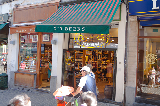 People are passing shops and store with 250 belgian beers in Brussels in street Rue au Beurre near Grand Place. In street are several gourmet and sweet stores, street is popular tourist area for shopping