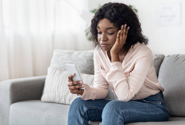 istock Boredom. Sad Black Girl Spending Time With Smartphone At Home 1271730320