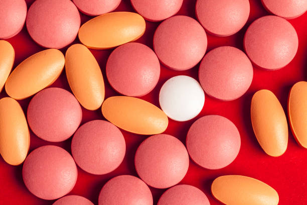 istock Many medicine pills close up on red background 1271731186