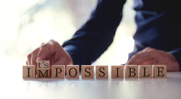 Businessman Changing The Word Impossible To Possible By Flipping Over Wooden Cube. stock photo